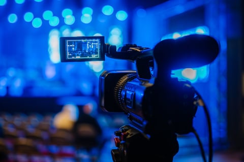 Video camera on tripod focused on live performance stage