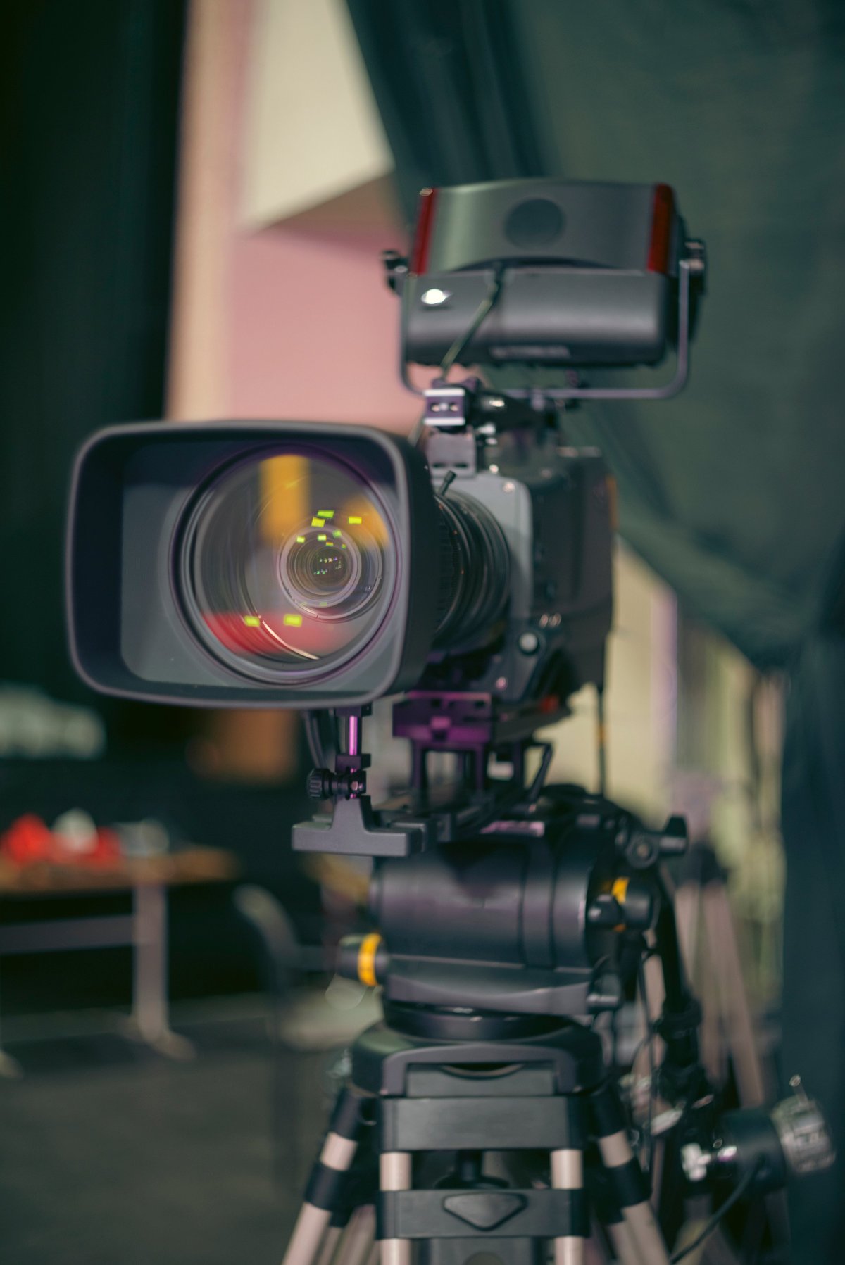 Professional digital television camera with monitor on a tripod, cinematic studio background