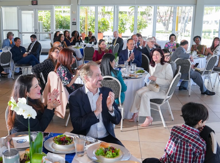 Large group of business professionals dining at an indoor corporate event or reception with food and beverages on tables